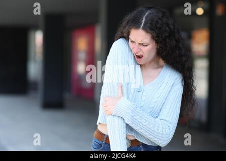 Femme stressée souffrant de douleurs au coude dans la rue Banque D'Images