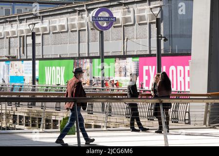 Les personnes qui voyagent en métro à Londres ont un peu d'air frais sous le soleil de l'été à l'extérieur de la station Elizabeth Line, Londres, Angleterre, Royaume-Uni Banque D'Images