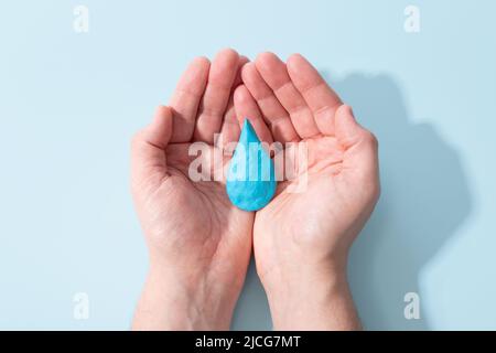 Tenir la goutte d'eau de la plasticité bleue modélisation argile Mans mains. Journée mondiale de l'eau, eau propre et assainissement, désinfectant pour les mains et hygiène, lavage des mains Banque D'Images