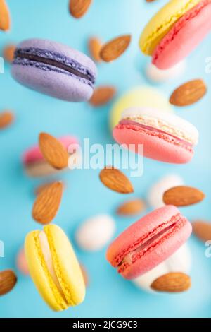 Macarons volants multicolores et œufs d'amandes congelés dans l'air sur fond bleu flou. Vue de dessus, plat, gros plan. Petit déjeuner, matin, concept Banque D'Images