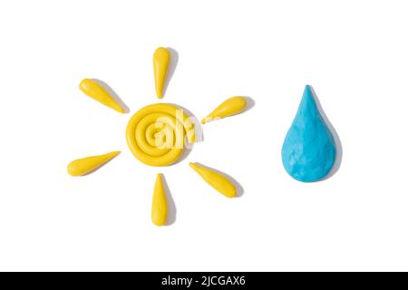 Plastique jaune modelage doigt argile soleil texturé et bleu goutte d'eau avec ombre isolée sur fond blanc. Vue de dessus, espace de copie. Banque D'Images