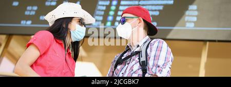 Couple attendant le vol avec des billets et portant un masque facial Banque D'Images