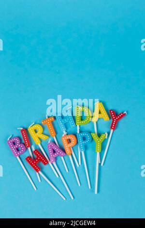 Bougies colorées en lettres avec lettrage « Happy Birthday » isolé sur fond bleu Banque D'Images