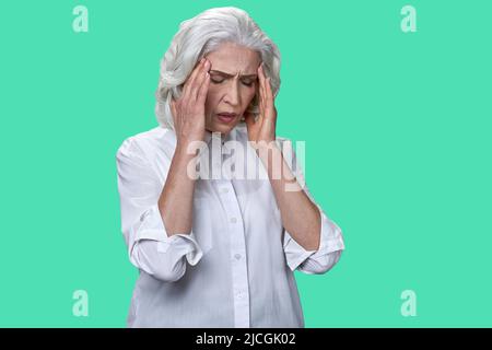 Femme d'affaires mature souffrant de migraine sur fond de couleur. Grand-mère ayant de forts maux de tête. Banque D'Images