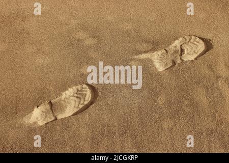 Traces de chaussures dans le sable. Empreintes de pas dans le sol sablonneux. Banque D'Images