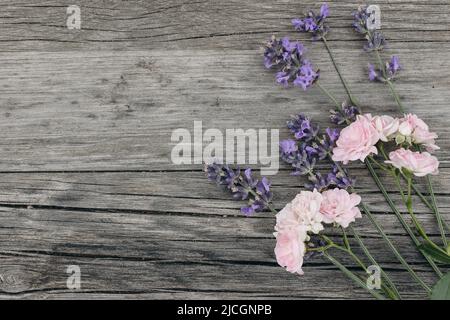 Bouquet de fleurs de lavande et de petites roses roses roses sur fond de table en bois. Cadre floral décoratif, bannière en toile avec Lavandula officinalis Banque D'Images