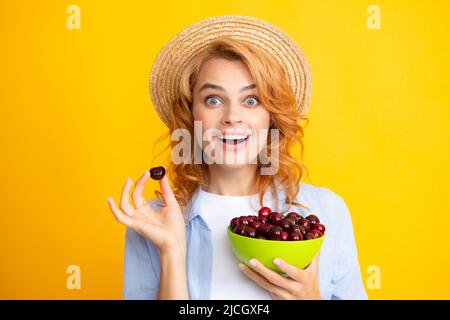 Jeune femme élégante isolée tenant des cerises rouges colorées. Saison de récolte des baies. Régime d'été avec cerise de récolte biologique. Banque D'Images