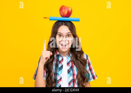 Retour à l'école. Adolescente avec pomme sur la tête, prête à apprendre. Les écoliers sur fond jaune isolé. Banque D'Images