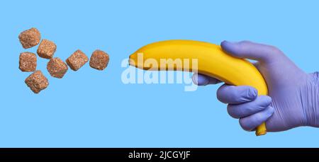 Une main dans un gant en latex contient une banane qui tire du sucre. Teneur élevée en glucides rapides dans les fruits doux. Concept de régime diabétique Banque D'Images