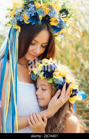 Mère et fille dans des couronnes ukrainiennes traditionnelles drapeau bleu et jaune de l'Ukraine. Famille, unité, soutien. Les Ukrainiens sont contre la guerre. Femme et enfant. La liberté à l'Ukraine. Arrêter l'agression russe. Banque D'Images