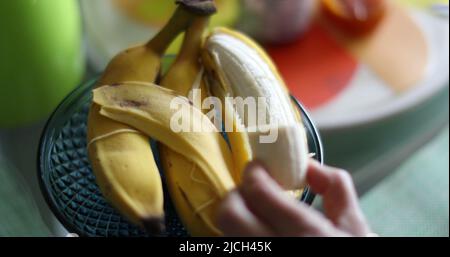 Gros plan à la main coupant la banane, personne épluchant la banane de fruit Banque D'Images