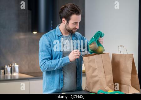 Homme regardant les fruits sortir du sac Banque D'Images