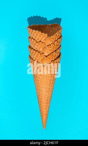 Une pile de cornets de glace gaufrée sur fond bleu en lumière intense. Banque D'Images