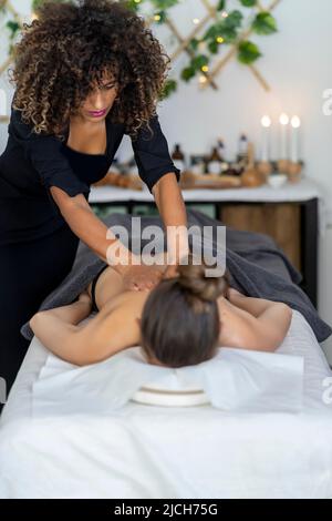 masseuse professionnelle effectuant un massage relaxant à son client Banque D'Images