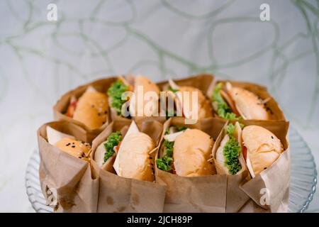 Un groupe de HAMBURGERS faits maison est enveloppé de papier artisanal et disposé sur le plat, prêt à servir et à manger. Banque D'Images