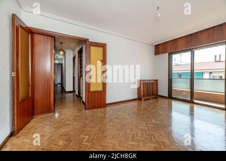 Séjour vide d'un appartement avec parquet, radiateurs en aluminium blanc, murs fraîchement peints de couleur blanche et porte d'accès en hêtre WO Banque D'Images