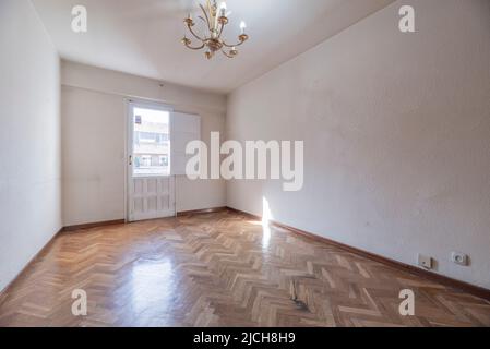 Séjour vide avec sortie sur terrasse avec porte en bois blanc en deux pièces et parquet en chêne à chevrons Banque D'Images