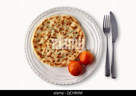 Pain plat au fromage et aux herbes garni de tomates sur une assiette blanche avec des couverts isolés sur un fond blanc. Vue de dessus. Pose à plat Banque D'Images