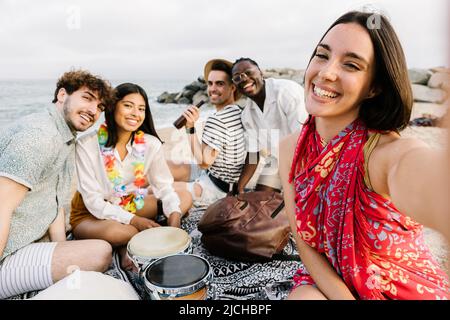 Jeune groupe d'amis divers prenant le selfie tout en se relaxant à la plage Banque D'Images