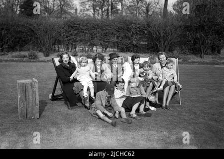 1950s, historique, grande photo de famille dans un jardin, plusieurs mères assis dans des chaises longues avec leurs jeunes enfants, Angleterre, Royaume-Uni. Banque D'Images