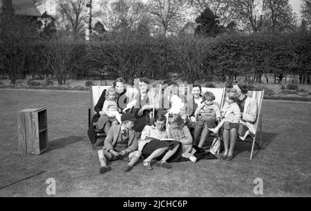 1950s, historique, grande photo de famille dans un jardin, plusieurs mères assis dans des chaises longues avec leurs jeunes enfants, Angleterre, Royaume-Uni. Banque D'Images