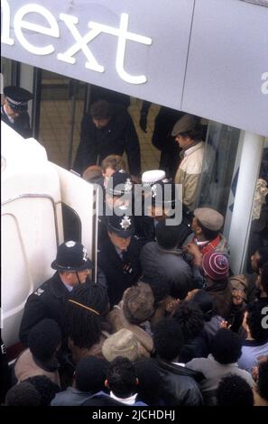 Les policiers gardent l'entrée de la prochaine boutique où Clinton McCurbin est mort alors qu'elle était arrêtée par la police à Wolverhampton. L'ambulance est adossée à la porte pour enlever le corps. 20 février 1987 Banque D'Images