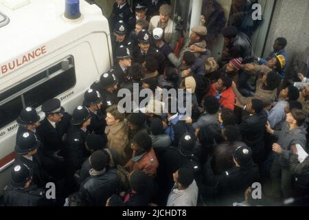 Les policiers gardent l'entrée de la prochaine boutique où Clinton McCurbin est mort alors qu'elle était arrêtée par la police à Wolverhampton. L'ambulance est adossée à la porte pour enlever le corps. 20 février 1987 Banque D'Images