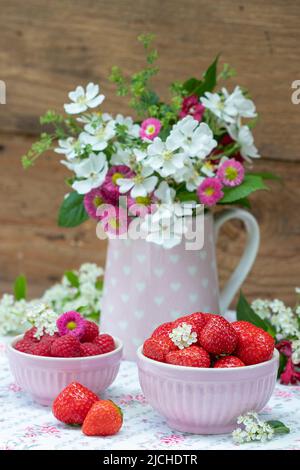 fraises fraîches et framboises en bols et bouquet de fleurs Banque D'Images