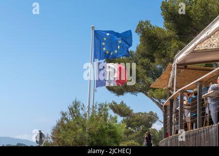 Le tricolore français et le drapeau de l'UE à côté d'un café en bord de mer sur la plage de Gigaro, Var, Provence-Alpes-Côte d'Azur, France. Banque D'Images