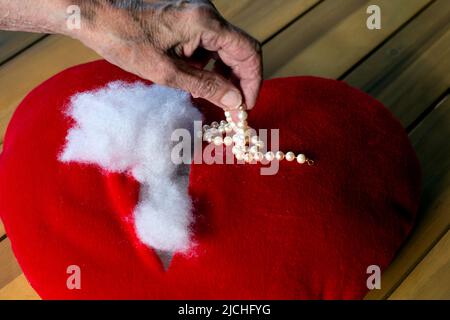 gros plan de femmes âgées à la main prenant des bijoux d'un coeur déchiré farci Banque D'Images