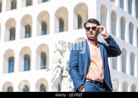 Homme d'affaires avec lunettes de soleil. Veste et chemise bleu. En arrière-plan un bâtiment. Banque D'Images