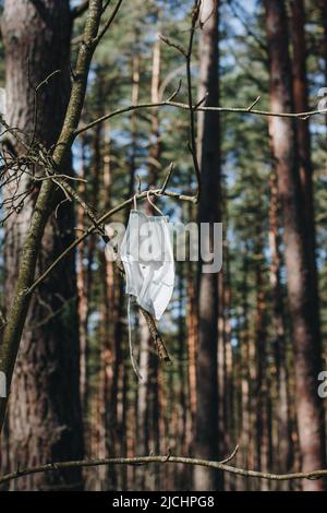 un seul morceau d'un masque chirurgical jetable protecteur gauche suspendu sur un arbre et en agitant sur le vent, oublié ou jeté masque soufflant dans le wi Banque D'Images