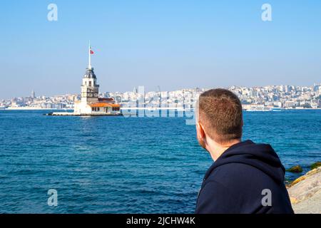 Homme assis en face de la mer et regardant la Tour Maidens à Istanbul Banque D'Images