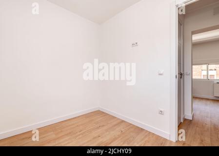 Chambre vide dans un appartement rénové avec murs peints en blanc, boiseries blanches et parquet en chêne Banque D'Images