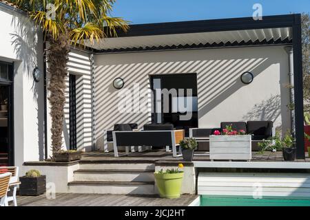 Patio extérieur tendance pergola structure d'ombre, auvent et toit de patio, salon de jardin, chaises, grill en métal entouré par l'aménagement paysager Banque D'Images