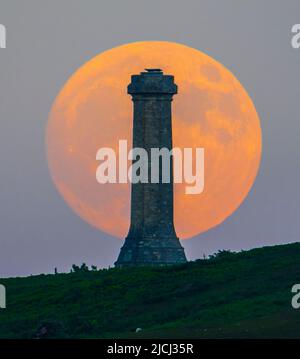 Portesham, Dorset, Royaume-Uni. 13th juin 2022. Météo Royaume-Uni. Le Strawberry Super Moon presque plein brille d'orange alors qu'il s'élève de derrière le monument Hardy à Portesham dans Dorset. Le monument a été construit en 1844 à la mémoire du vice-amiral Sir Thomas Masterman Hardy, capitaine de drapeau de la victoire du HMS à la bataille de Trafalgar. Crédit photo : Graham Hunt/Alamy Live News Banque D'Images