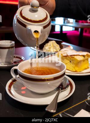 Temps du thé en Angleterre, verser du thé noir earl Grey avec bergamote dans une tasse, thé dînatoire servi café à Londres, gros plan Banque D'Images