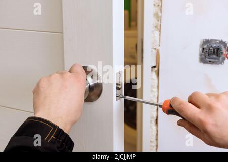 Le serrurier installe la serrure de porte dans la maison. Banque D'Images