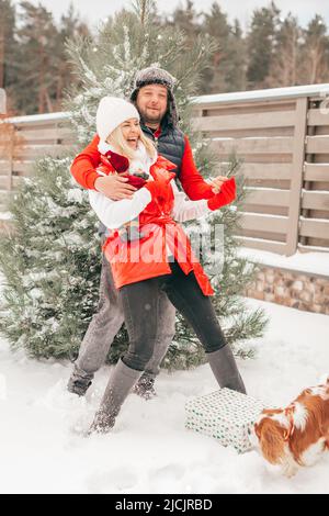 Couple heureux marchant dans le parc en hiver et jouant avec la neige, amusant jouer avec le chien, bonne relation Banque D'Images