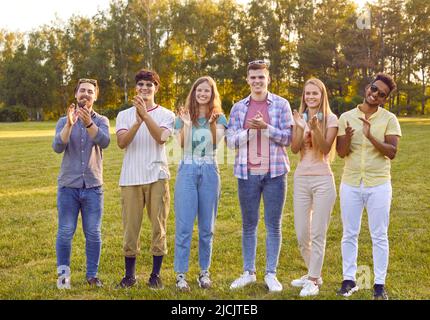 De jeunes amies gaies, femmes et hommes, applaudissent ensemble pendant la promenade estivale dans le parc. Banque D'Images