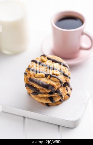 Biscuits aux pépites avec des arachides et des bandes de chocolat sur une table blanche. Banque D'Images