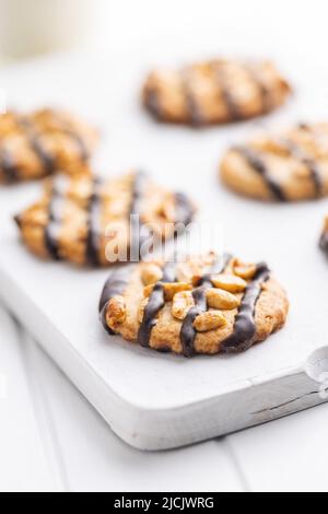 Biscuits aux pépites avec des arachides et des bandes de chocolat sur une table blanche. Banque D'Images