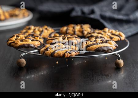 Biscuits aux pépites avec des arachides et des bandes de chocolat sur une table noire. Banque D'Images