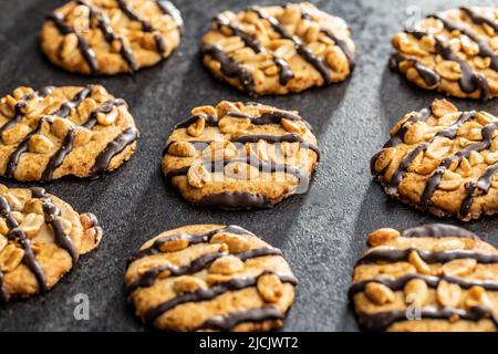 Biscuits aux pépites avec des arachides et des bandes de chocolat sur une table noire. Banque D'Images