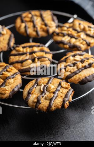 Biscuits aux pépites avec des arachides et des bandes de chocolat sur une table noire. Banque D'Images