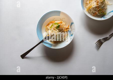 Nouilles frites servies dans un bol sur fond. Vue de dessus, mise au point sélective. Banque D'Images