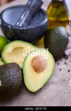 avocat frais coupé en deux et mortier de marbre sur table en béton gris Banque D'Images