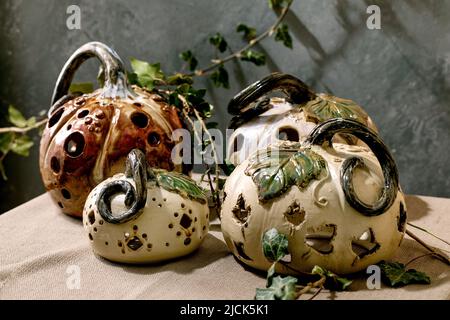 Décorations d'Halloween, ensemble de citrouilles en céramique sculptées blanches et brunes sur une table avec des feuilles de lierre. Halloween vacances intérieur maison d Banque D'Images