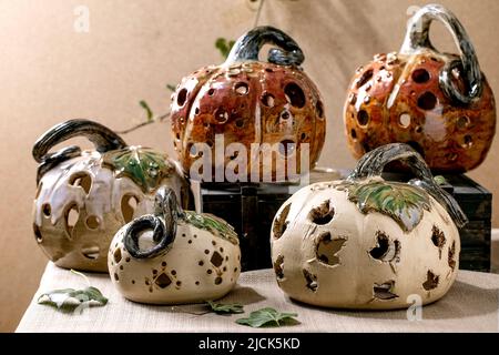 Décorations d'Halloween, ensemble de citrouilles en céramique sculptées blanches et brunes sur une table avec des feuilles de lierre. Fête d'Halloween ou de Thanksgiving Banque D'Images