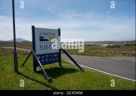 Panneau pour la boutique communautaire Uig sur l'île de Lewis avec des icônes pour le carburant, les magasins, les rafraîchissements etc. Route, champs, plage et mer en arrière-plan. Jour ensoleillé Banque D'Images